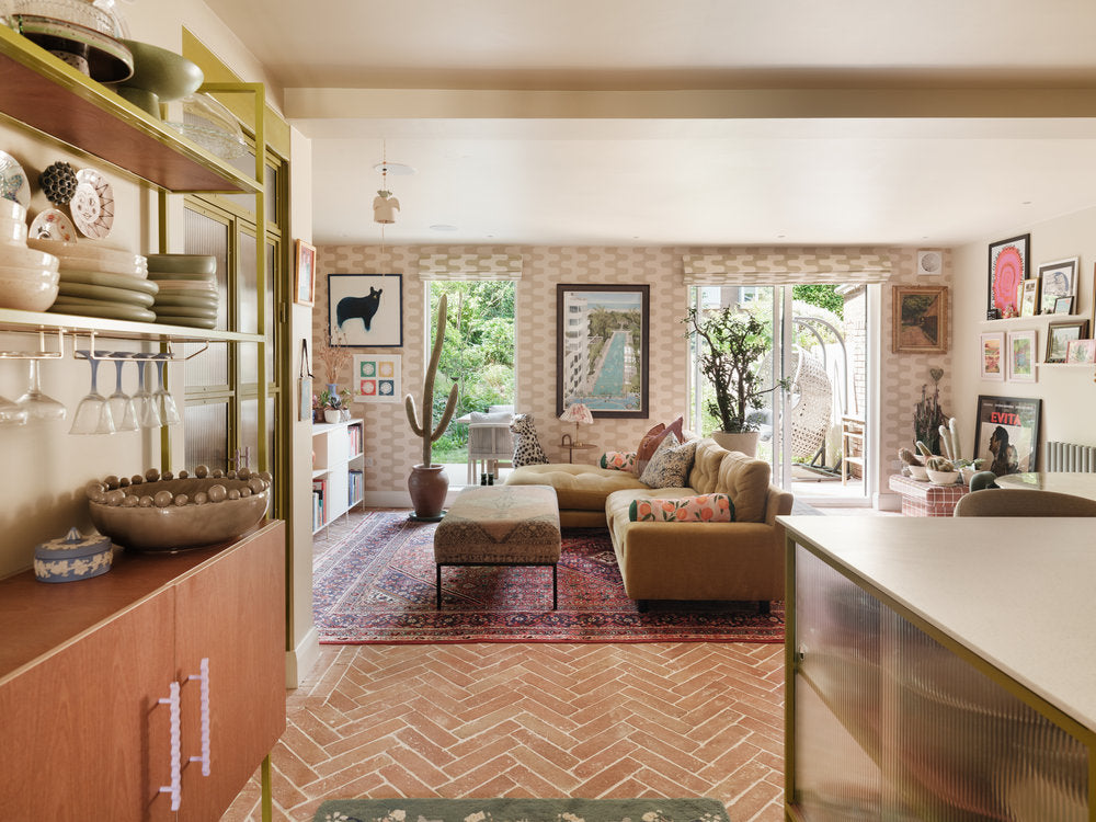 Californian-style open-plan kitchen and living space featuring the olive green mid-century dresser, a large sofa, and potted cacti.