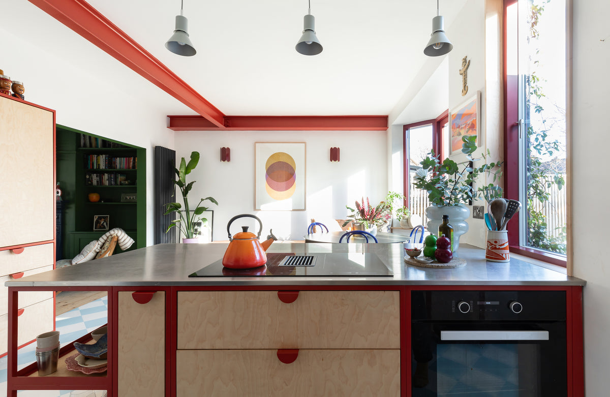 Bright red steel frame kitchen with birch plywood fronts and stainless steel work top, Le Creuset kettle