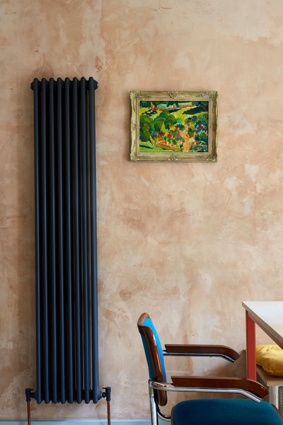 Raw plastered walls, vertical radiator, vintage oil painting, velvet blu chair 